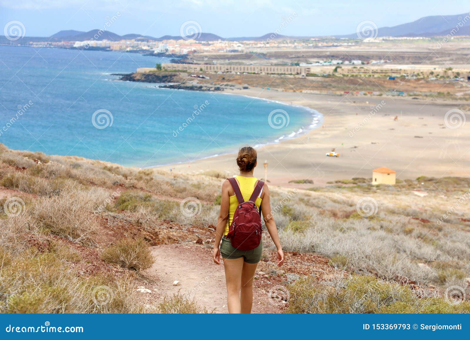 female hiker descent the pathway with spectacular landscape of playa la tejita beach, tenerife, canary islands