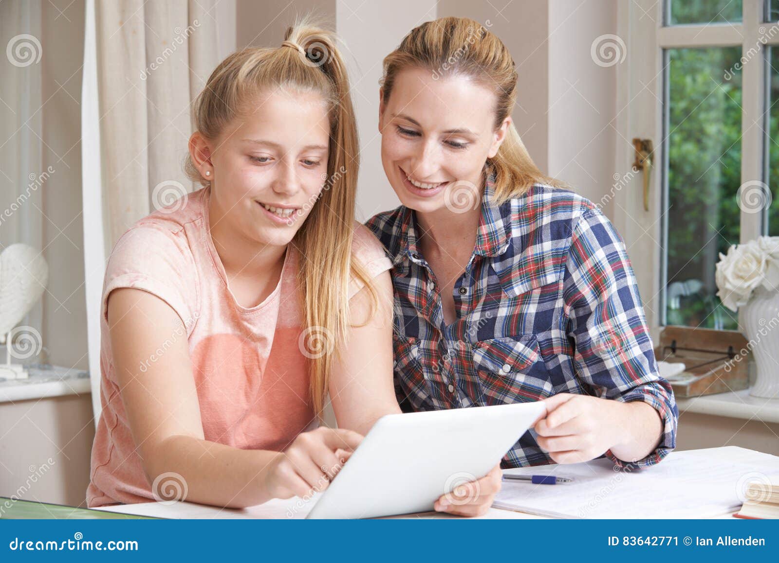 female home tutor helping girl with studies using digital tablet