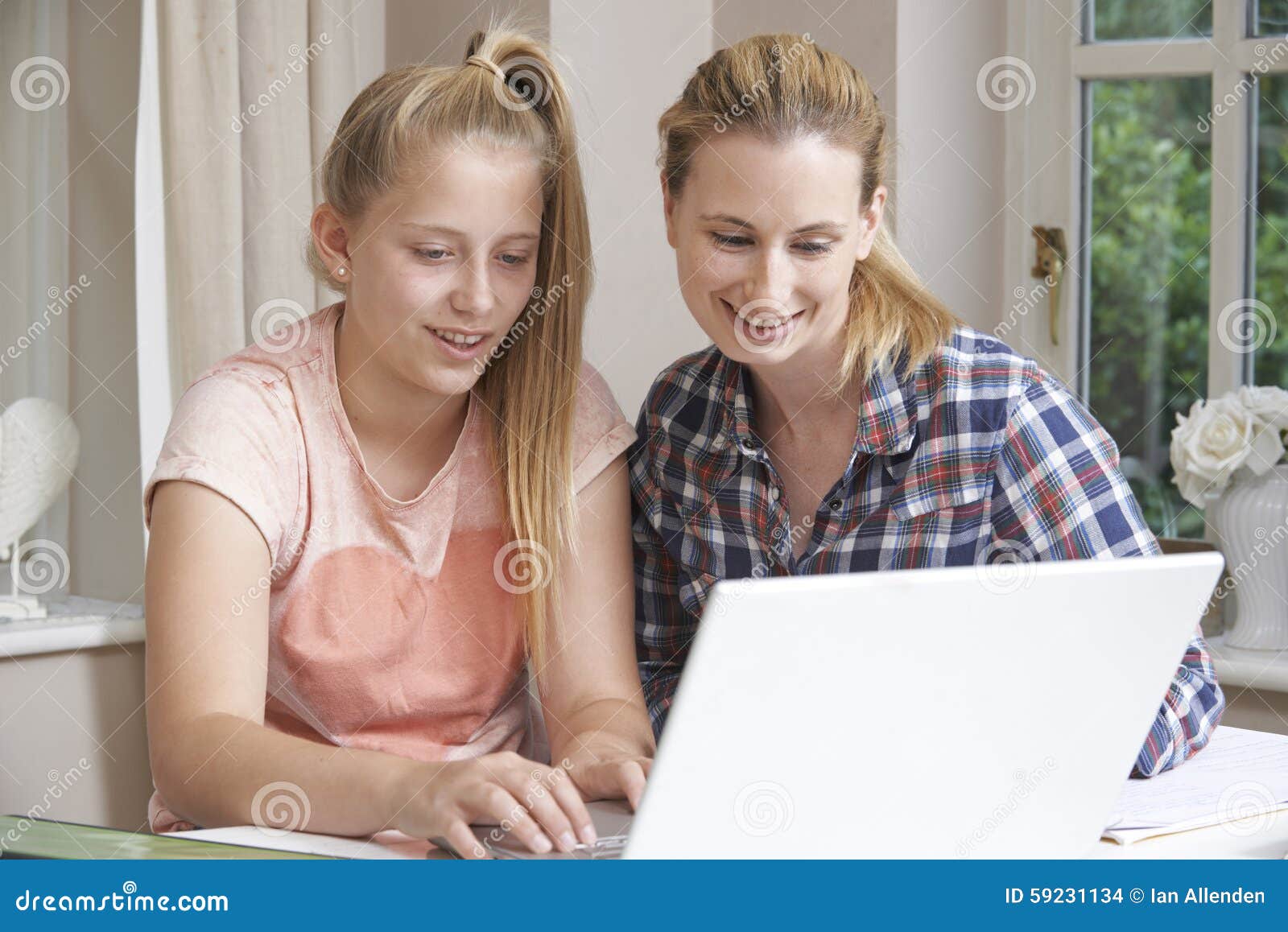 female home tutor helping girl with studies using laptop