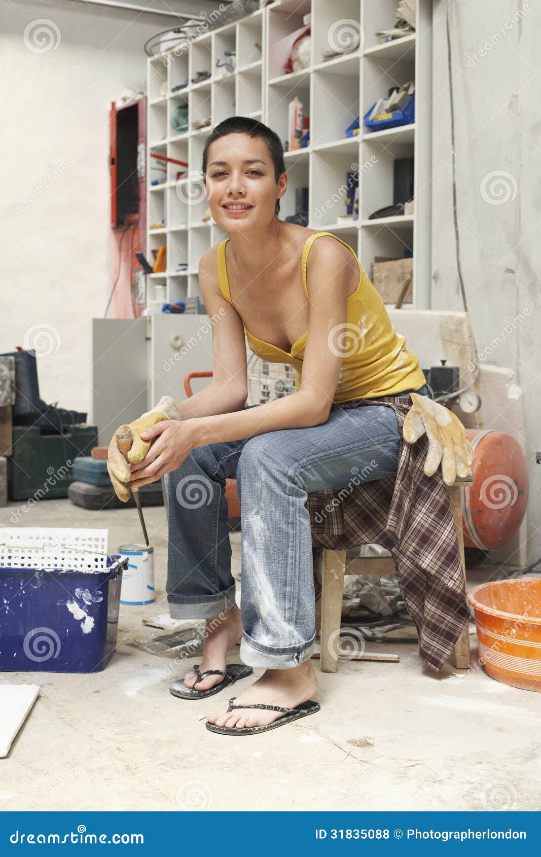Female Interior Decorator Sitting on Stool in Work Site Stock Photo