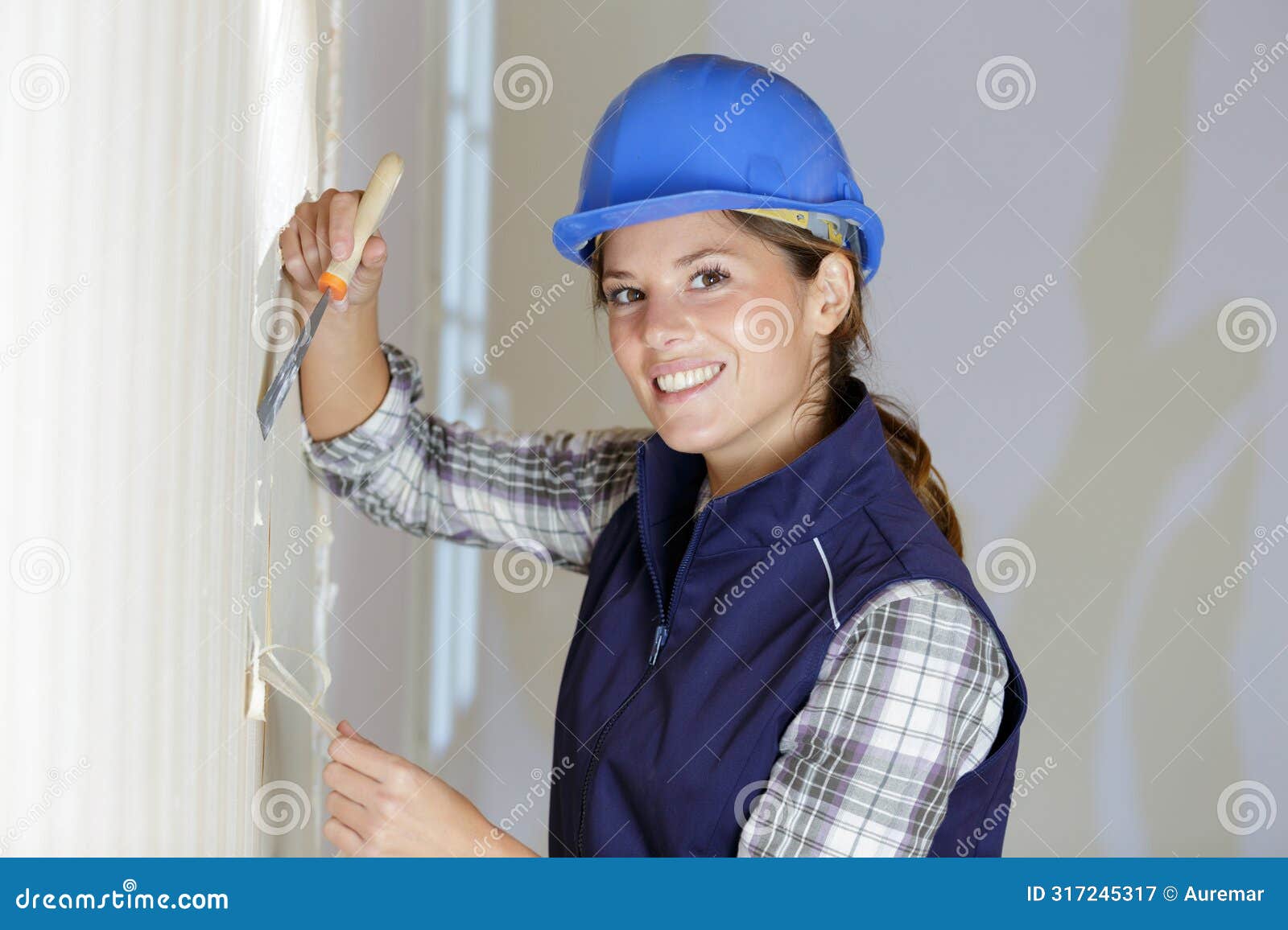 female labourer removing wallpaper in renovation property