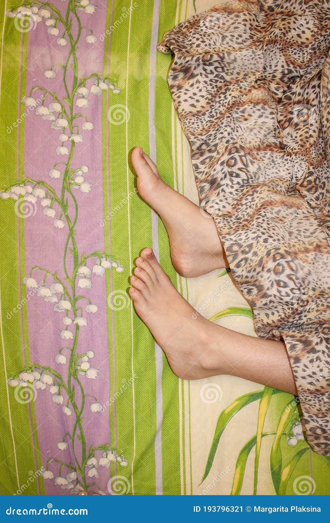Female Legs Sticking Out from Under the Covers on the Bed Stock Image