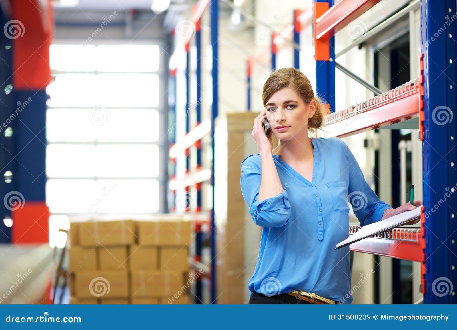 Female Logistics Worker on Mobile Phone in Warehouse Stock Image