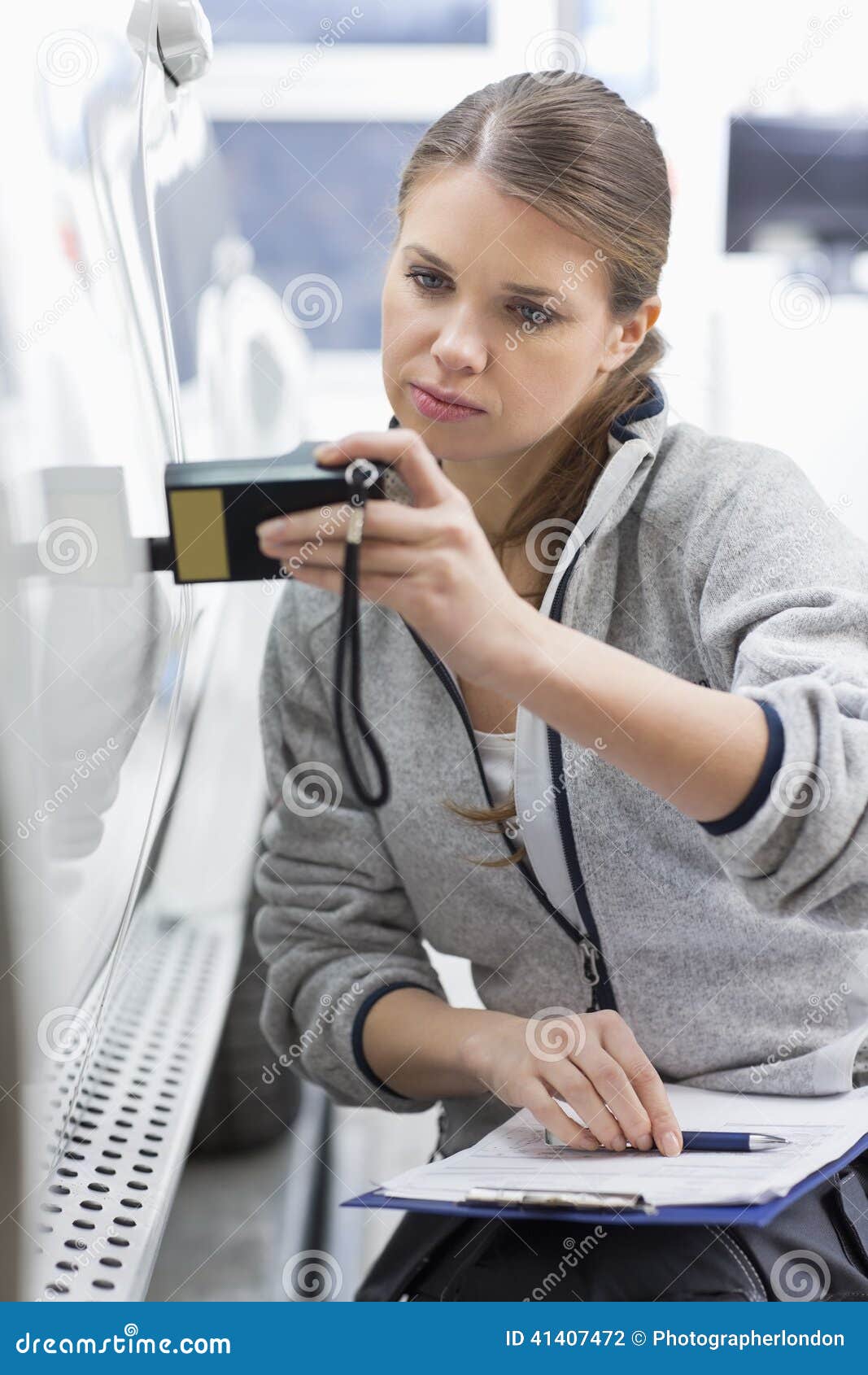 Female Maintenance Engineer Checking Car Paint with Equipment in