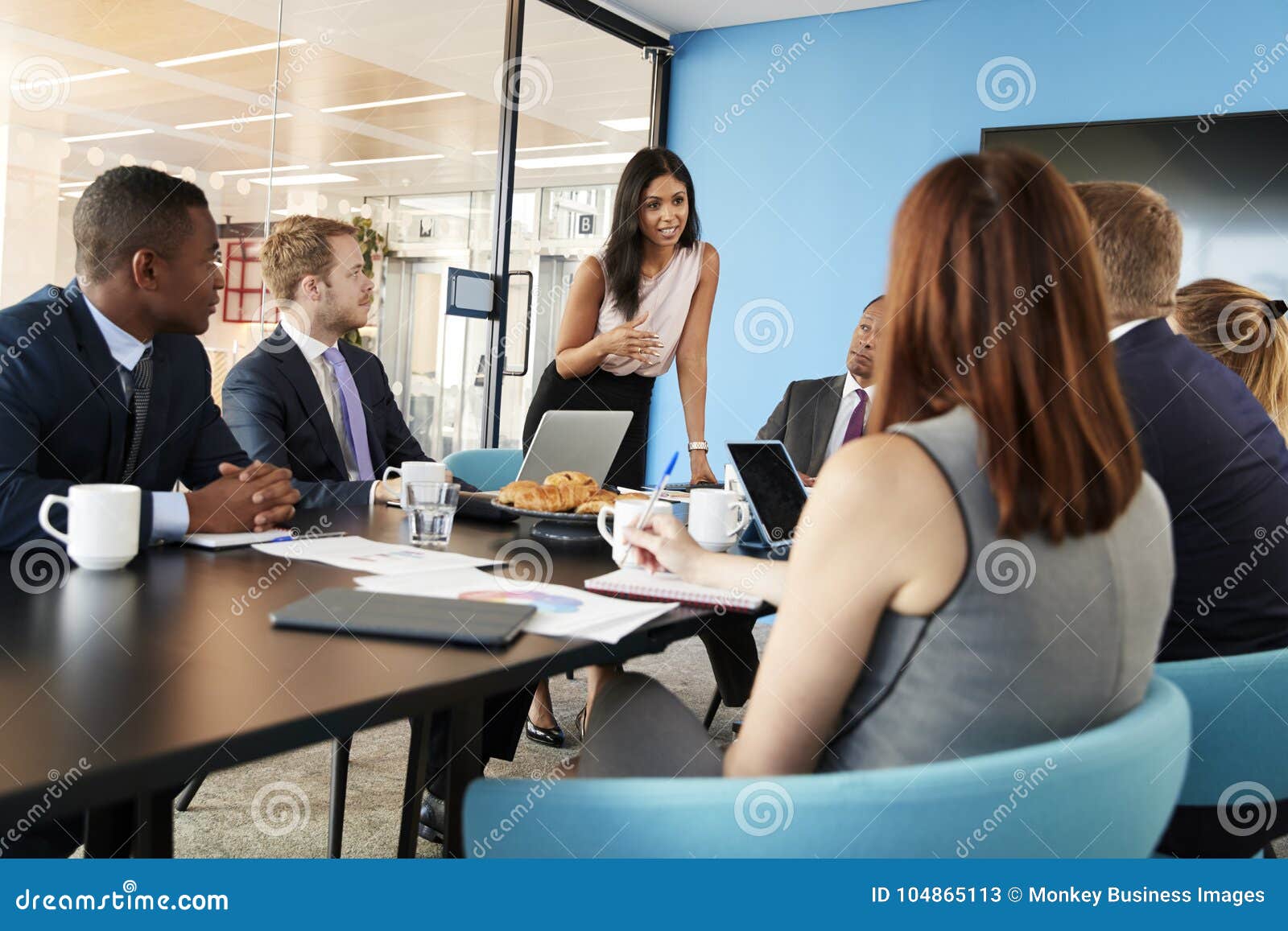 female manager stands addressing team at business meeting