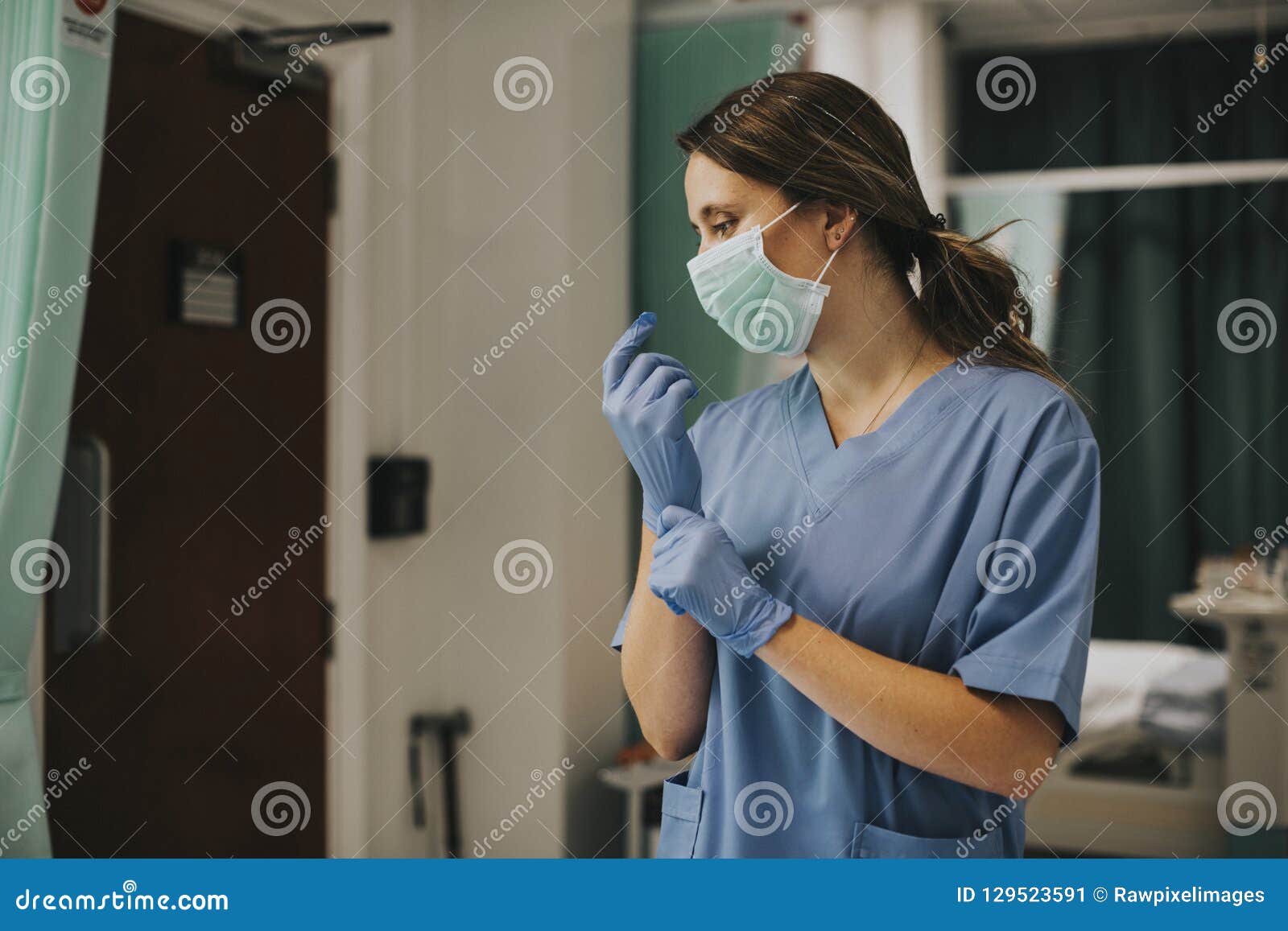 female nurse with a mask putting on gloves