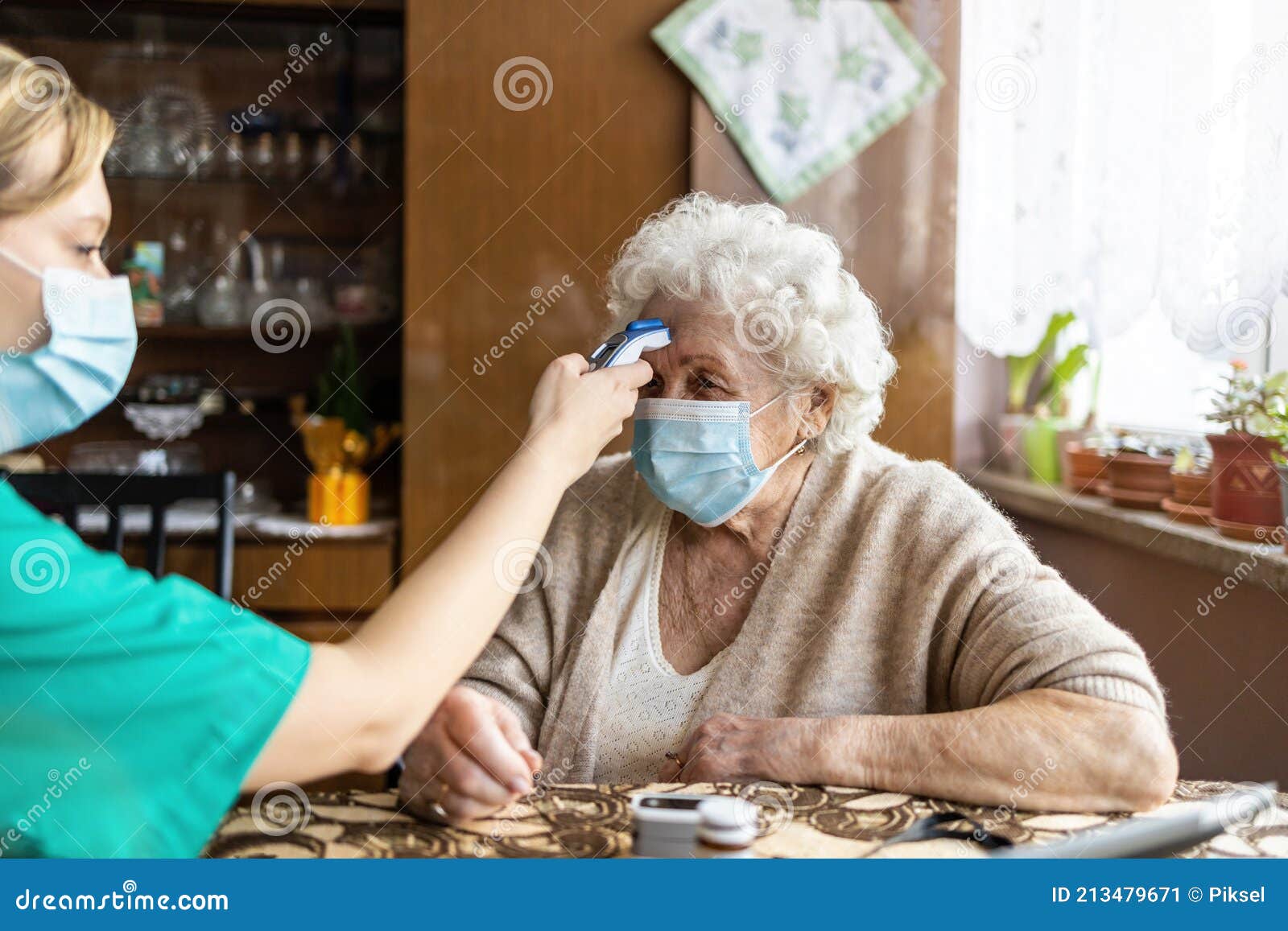 female nurse checking temperature to senior woman during home visit