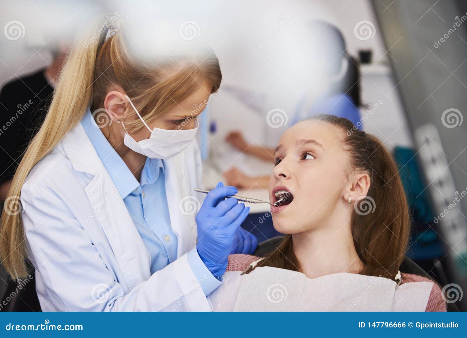 female orthodontist examining child`s teeth