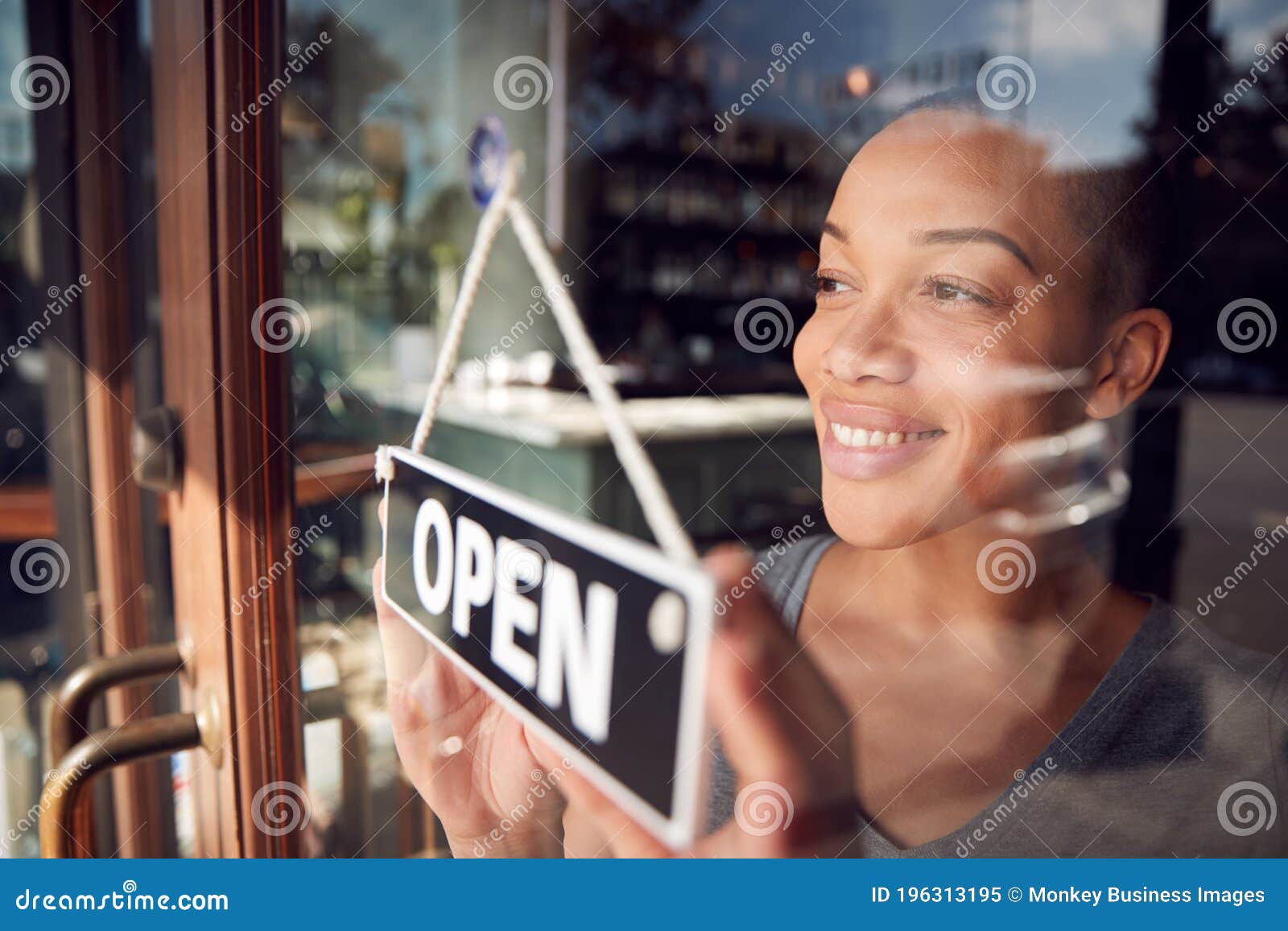 female owner of start up coffee shop or restaurant turning round open sign on door