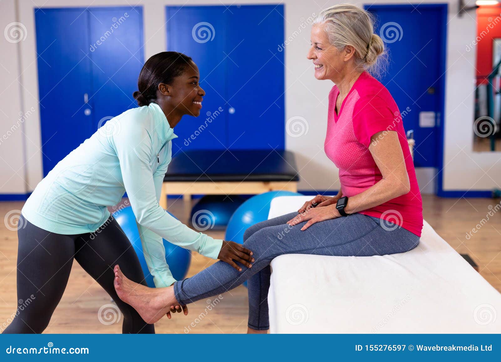 Female Physiotherapist Giving Leg Massage To Active Senior Woman In Sports Center Stock Image