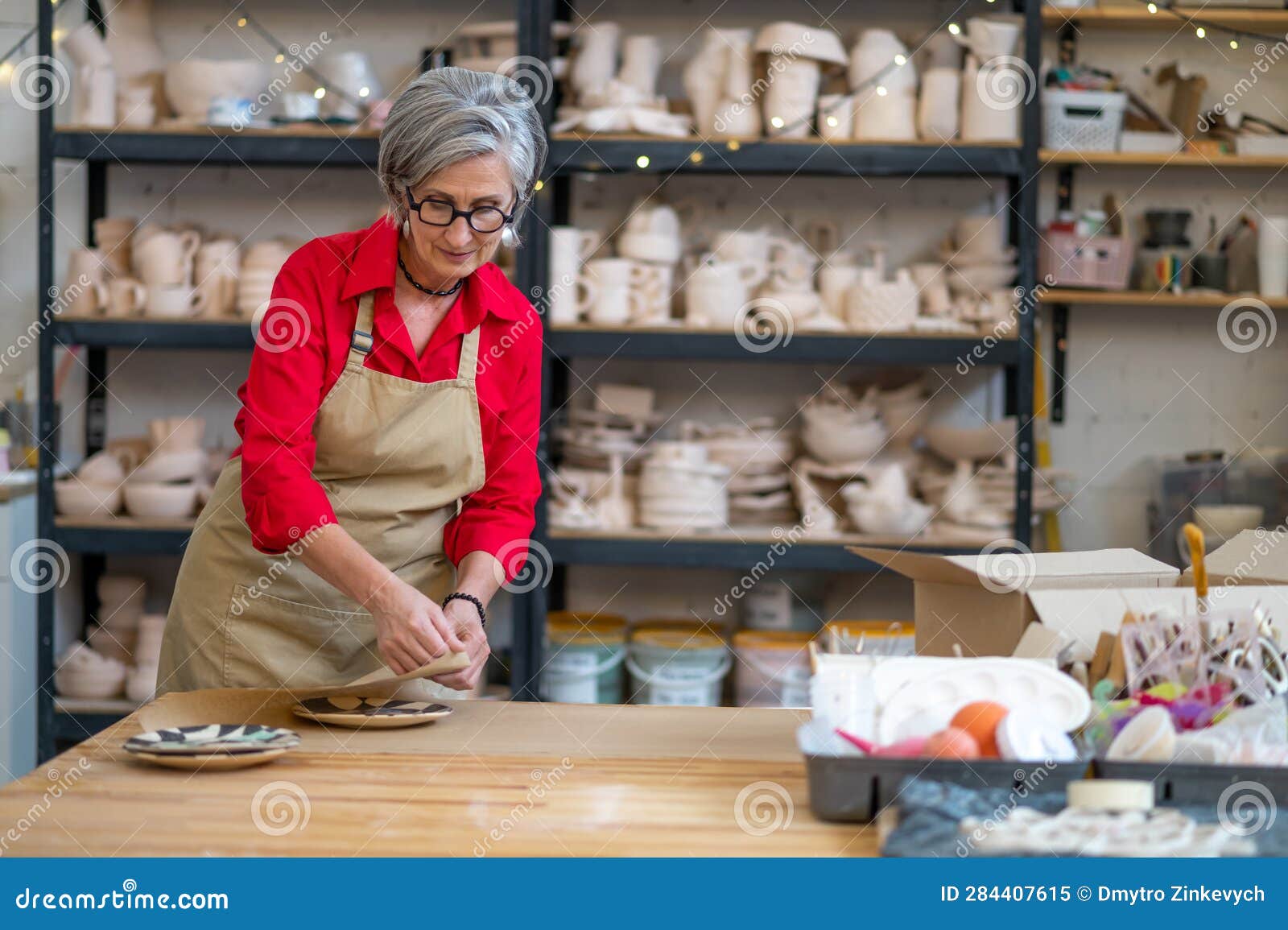 Female Pottery Master or Shop Assistant Wrapping Earthenware Item