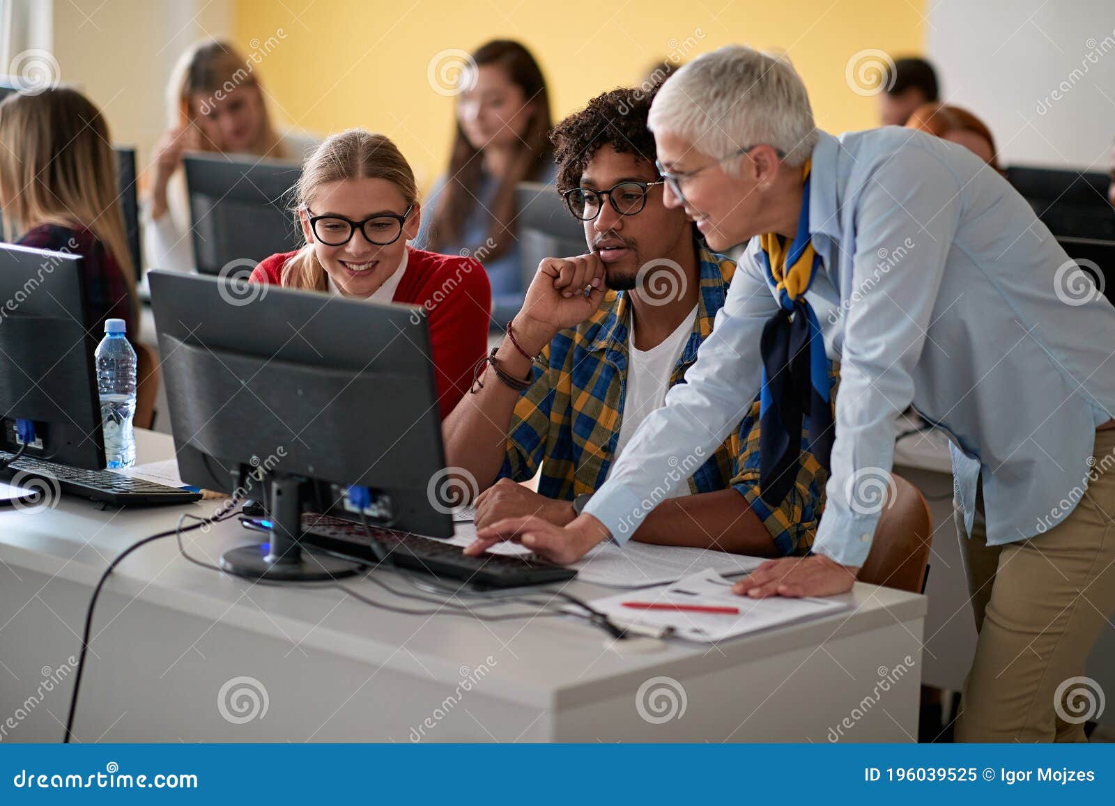 female professor correcting students errors at an informatics lecture