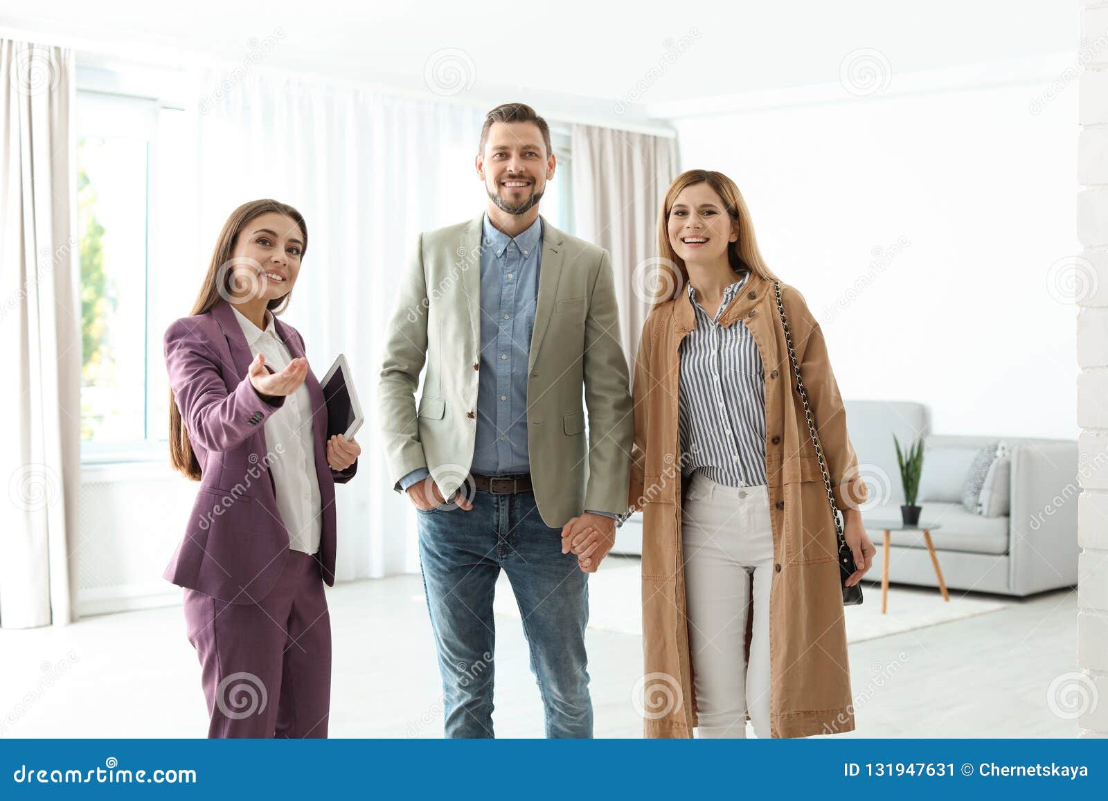 female real estate agent showing new house to couple