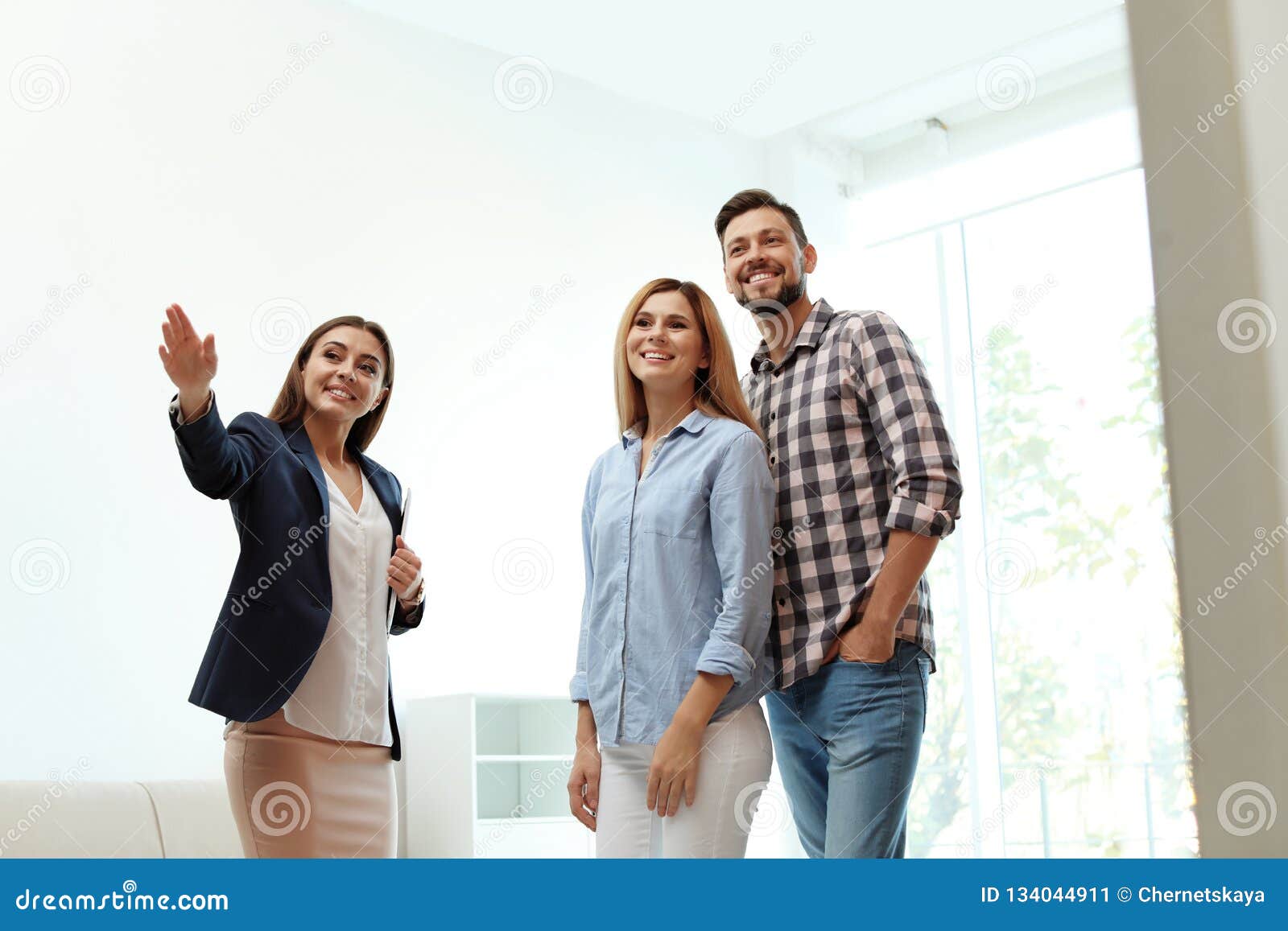 Female Real Estate Agent Showing New House To Couple Stock Image 