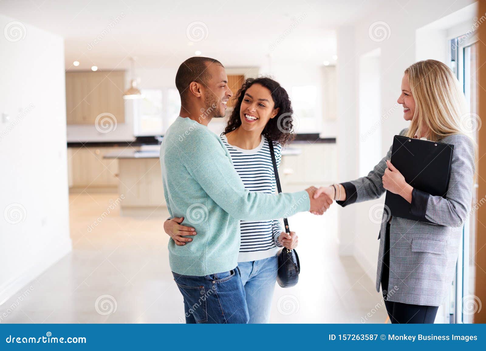 female realtor shaking hands with couple interested in buying house