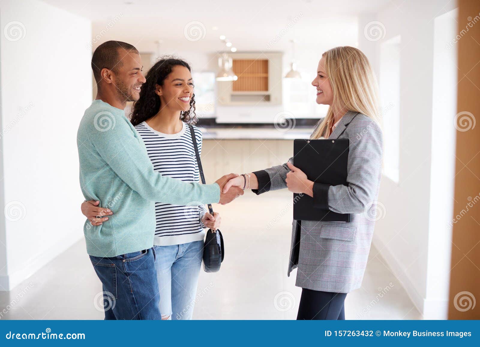 female realtor shaking hands with couple interested in buying house