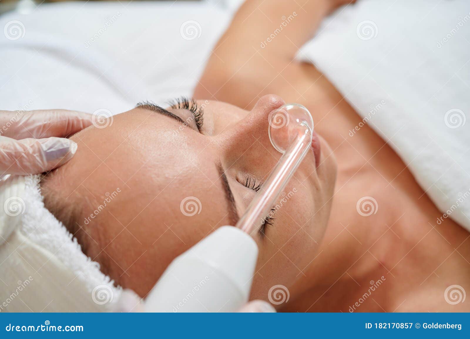 female receiving galvanic facial treatment in spa cosmetologist wearing gloves professional services