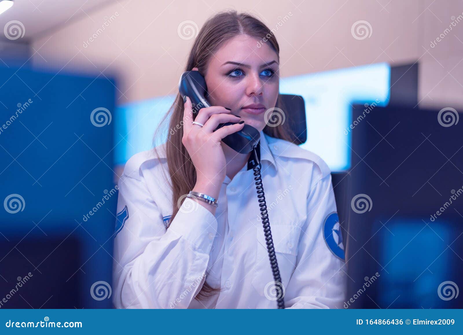 female security guard operator talking on the phone, calling in the alarming event to the external team of field force agents