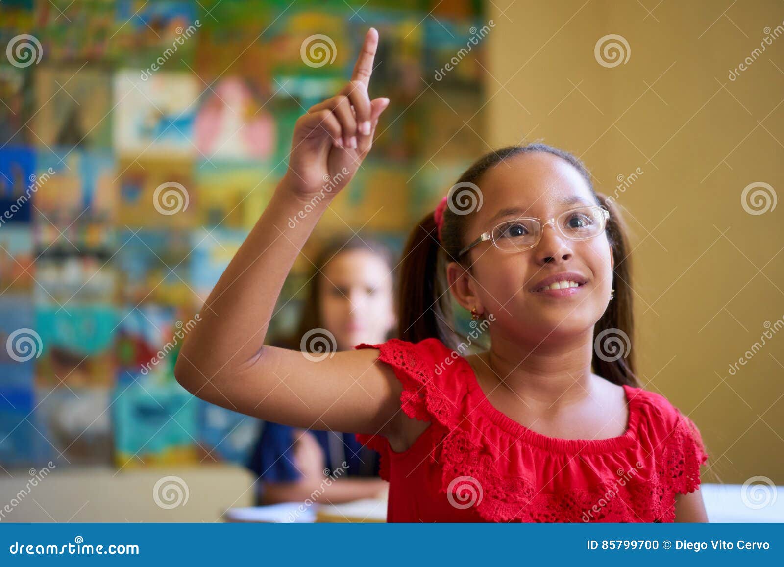 female student raising hand during test in class at school