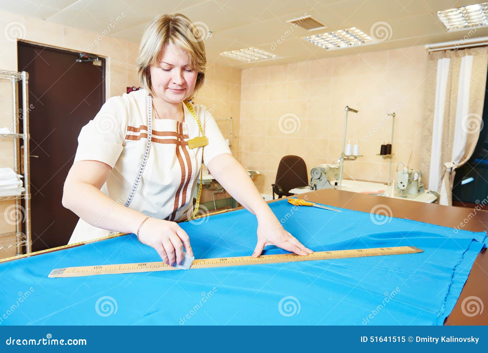 Female Tailor Employee Smiles While Sewing Using An Embroidery Machine