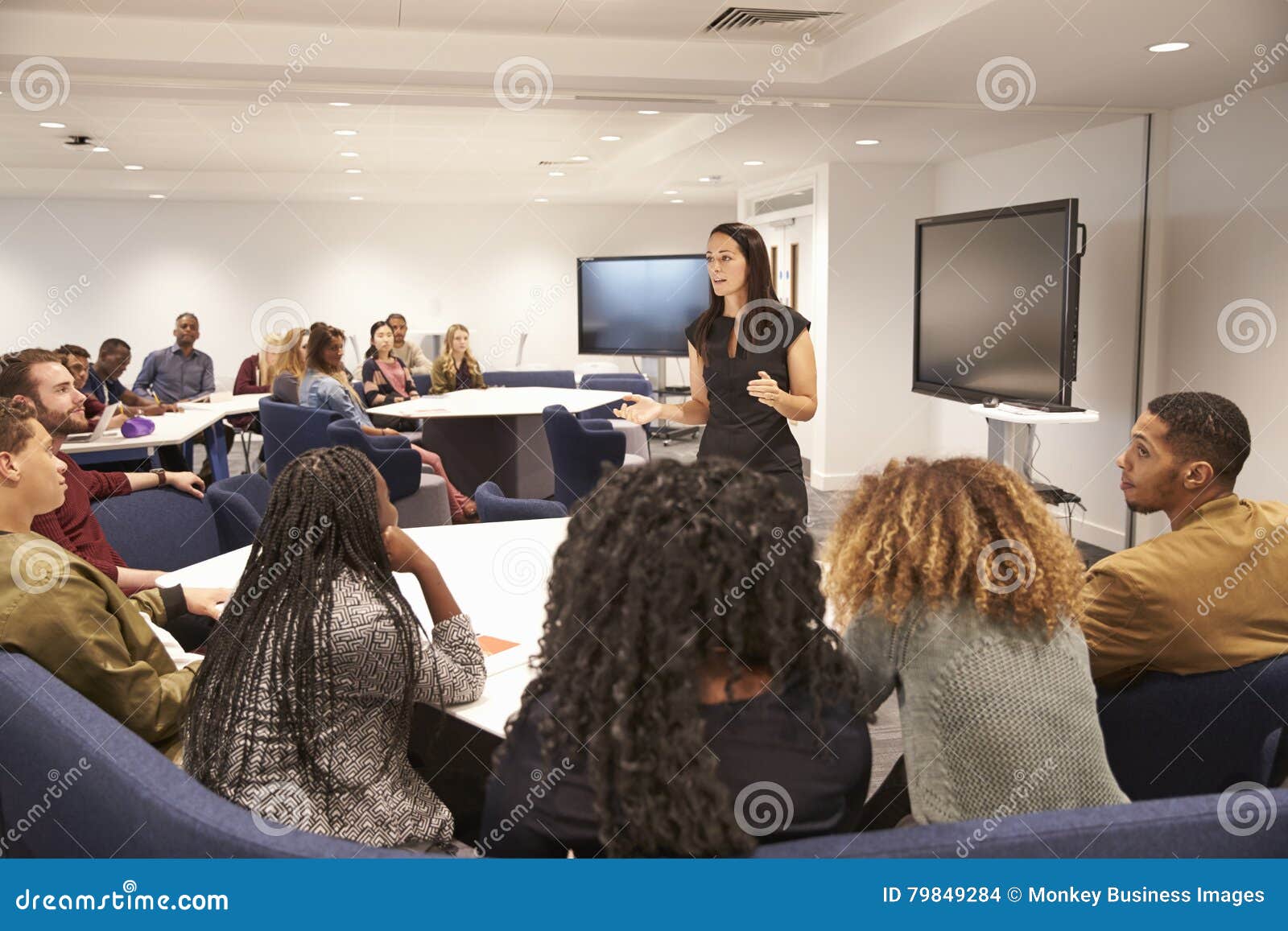 female teacher addressing university students in a classroom