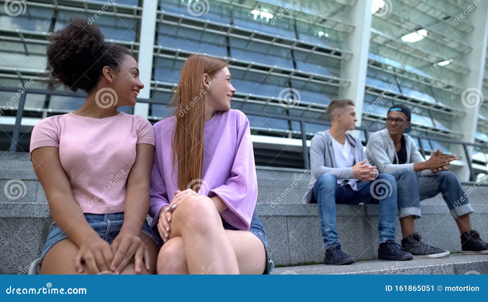 female teenagers looking at male students sitting stairs, first relations, flirt