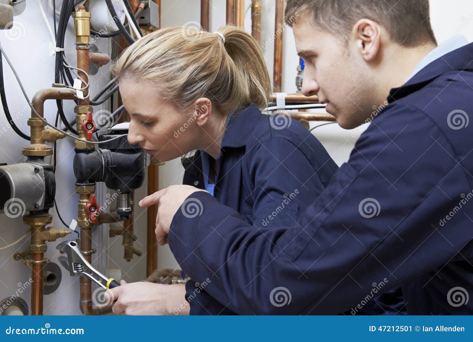female trainee plumber working on central heating boiler
