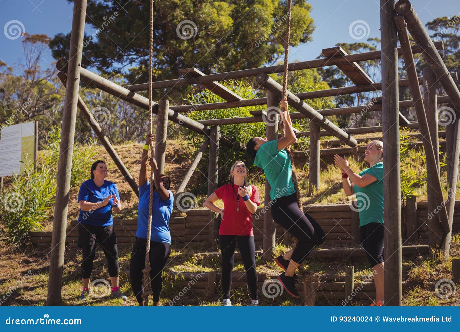 female trainer instructing women to climb a rope in the boot camp
