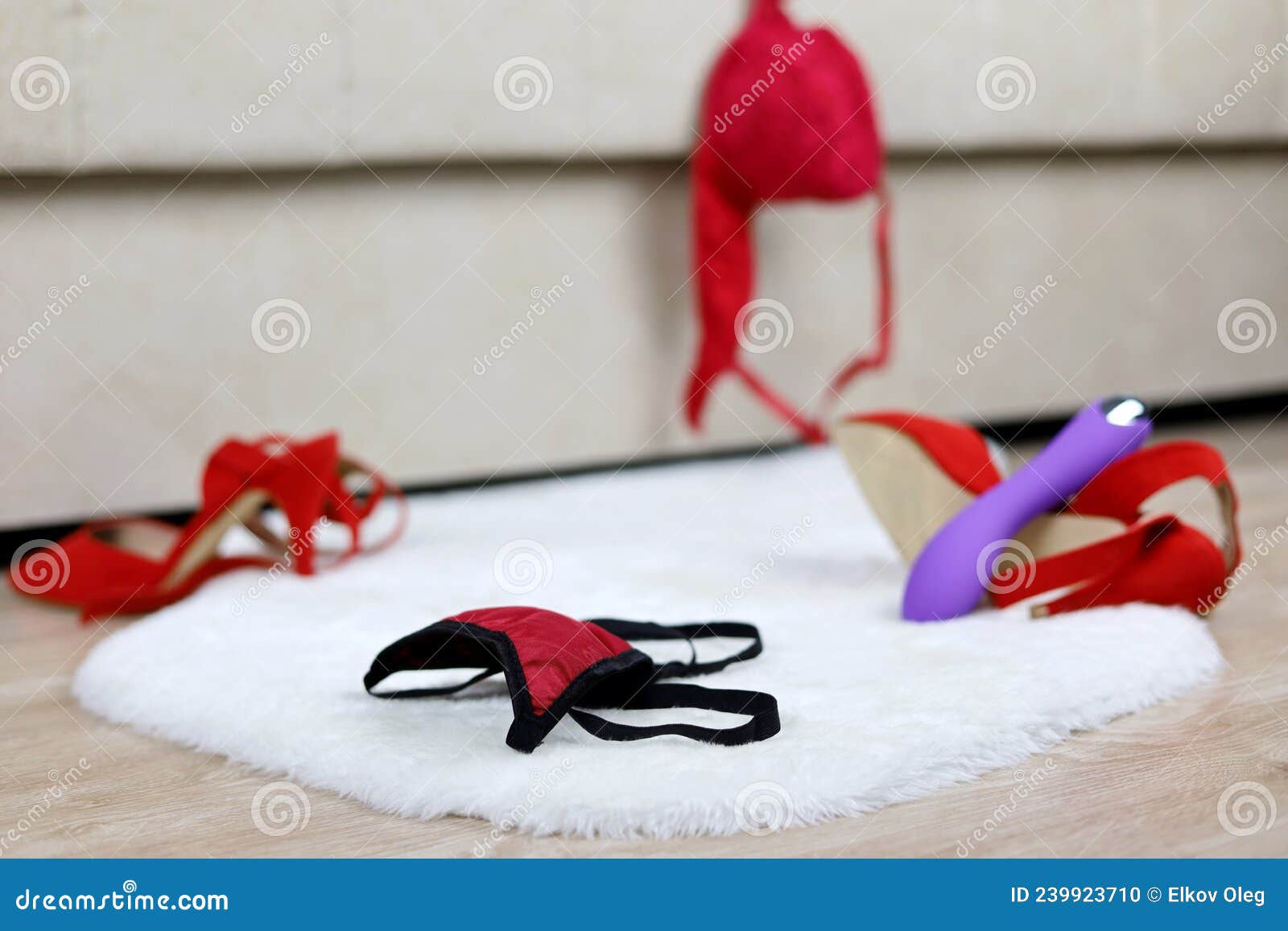 Female Thong Panties, Removed Red Bra and Shoes on a Floor Near Sofa Stock Photo
