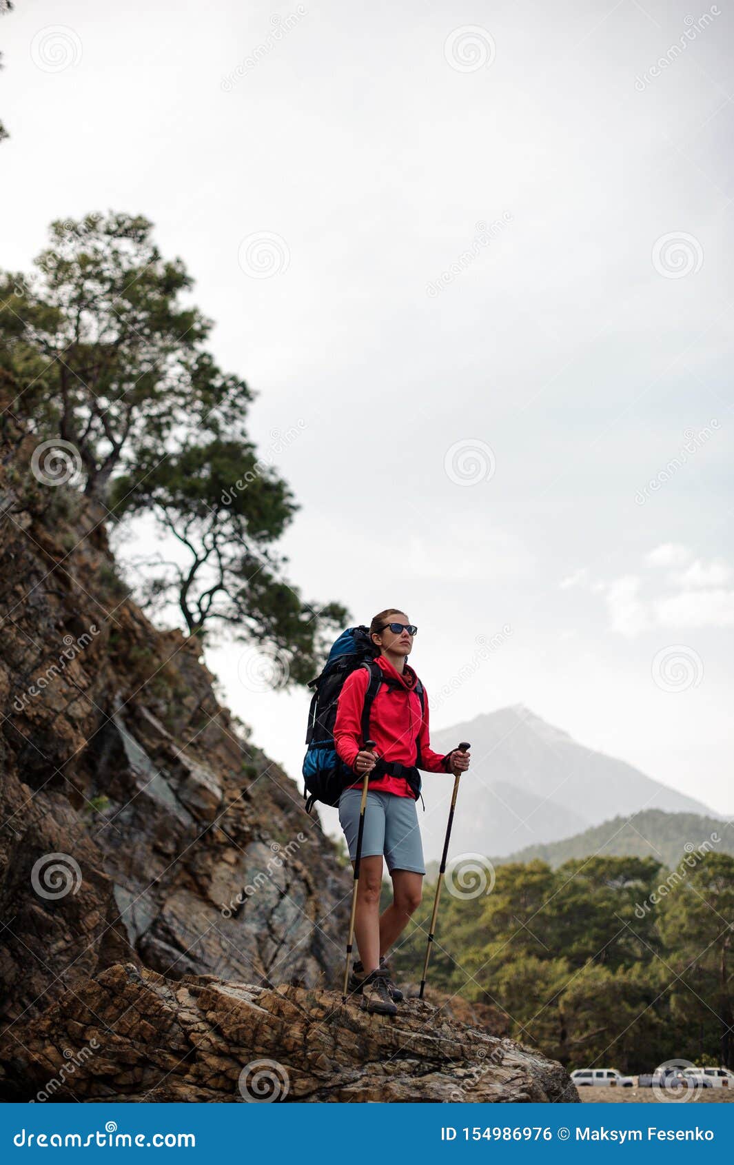 Tourist teens girl hiker with backpack cap and glasses is standing smile  and poses happily at