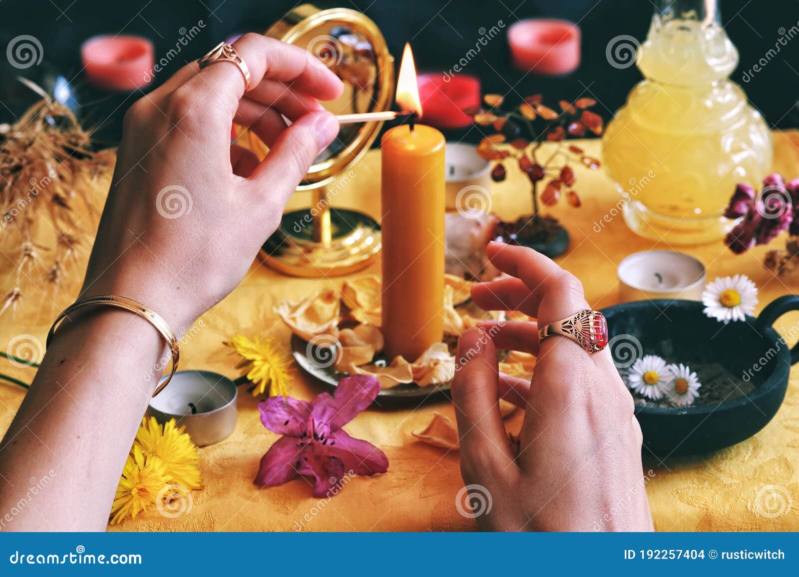 female wiccan witch wearing vintage jewelry lighting a yellow candle on her litha midsummer sabbat solstice celebration altar