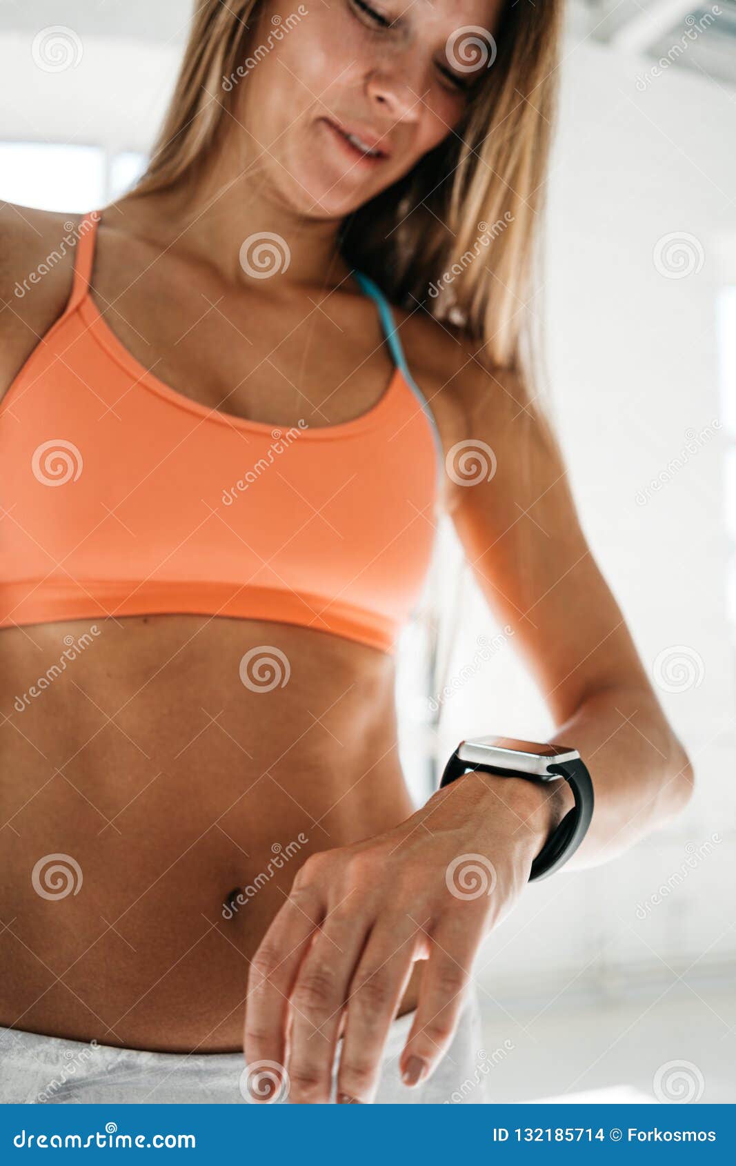 female after workout session checks results on smartwatch in fitness app. fit woman looks at smart watch and counts up spent calor