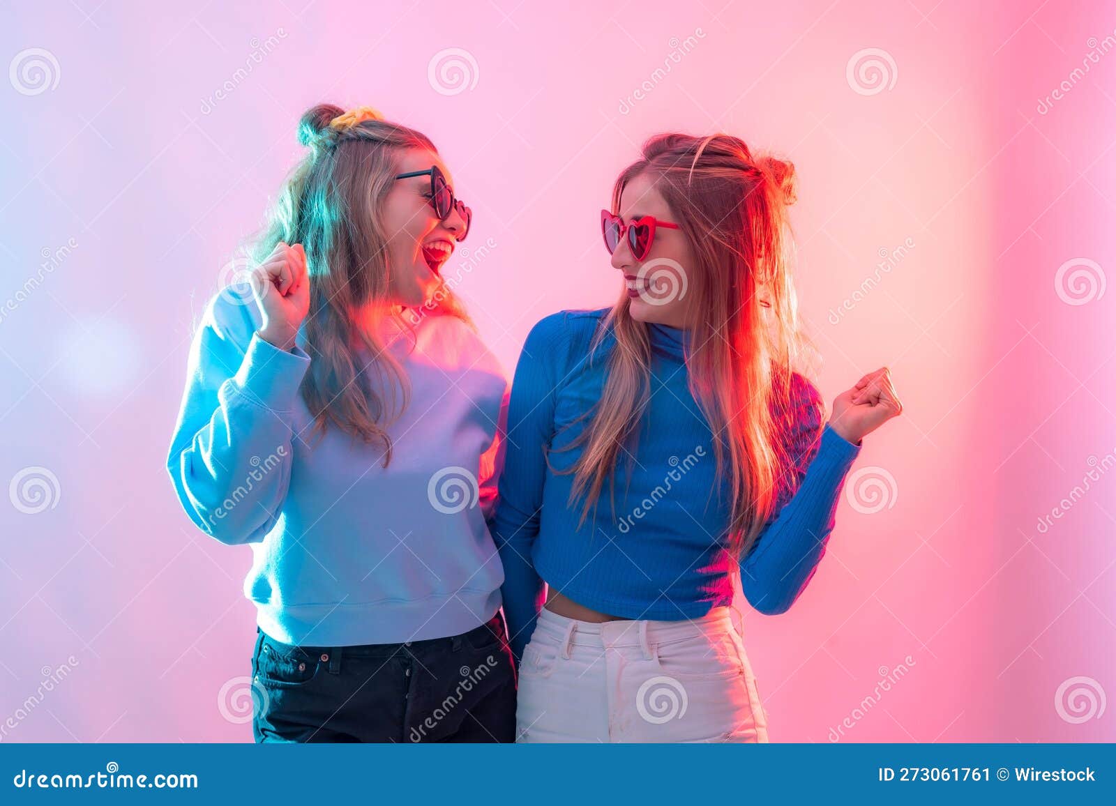 females embracing in a warm hug illuminated by bright neon lights creating clubbing atmosphere