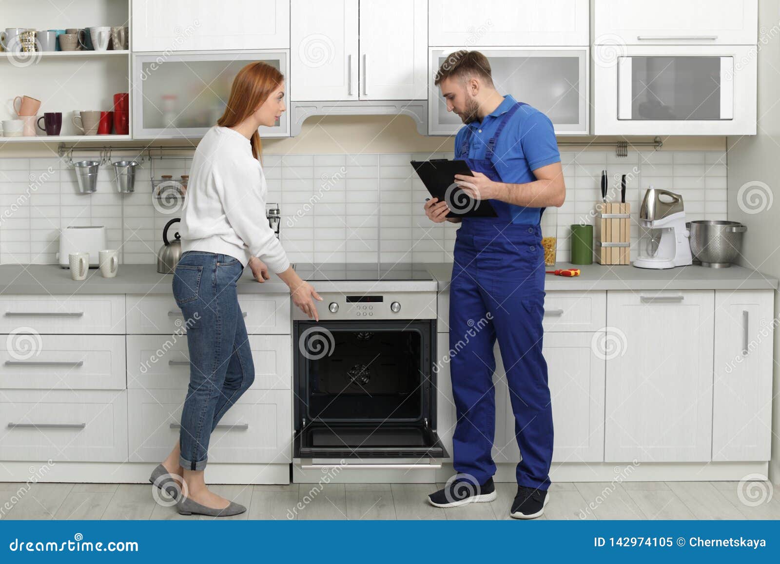 Femme au foyer avec le dépanneur près du four moderne dans la cuisine