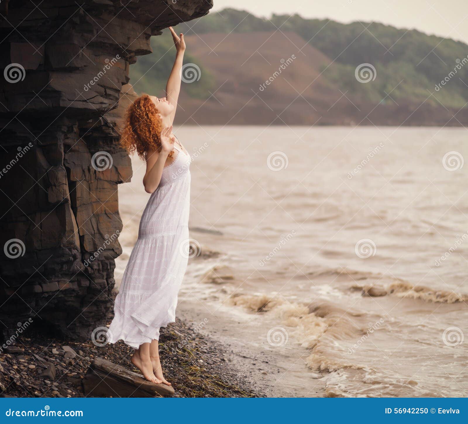 Femme dans la robe blanche se tenant sur la plage. Femme rousse dans la robe blanche se tenant sur la plage et regardant à quelque part Orientation molle