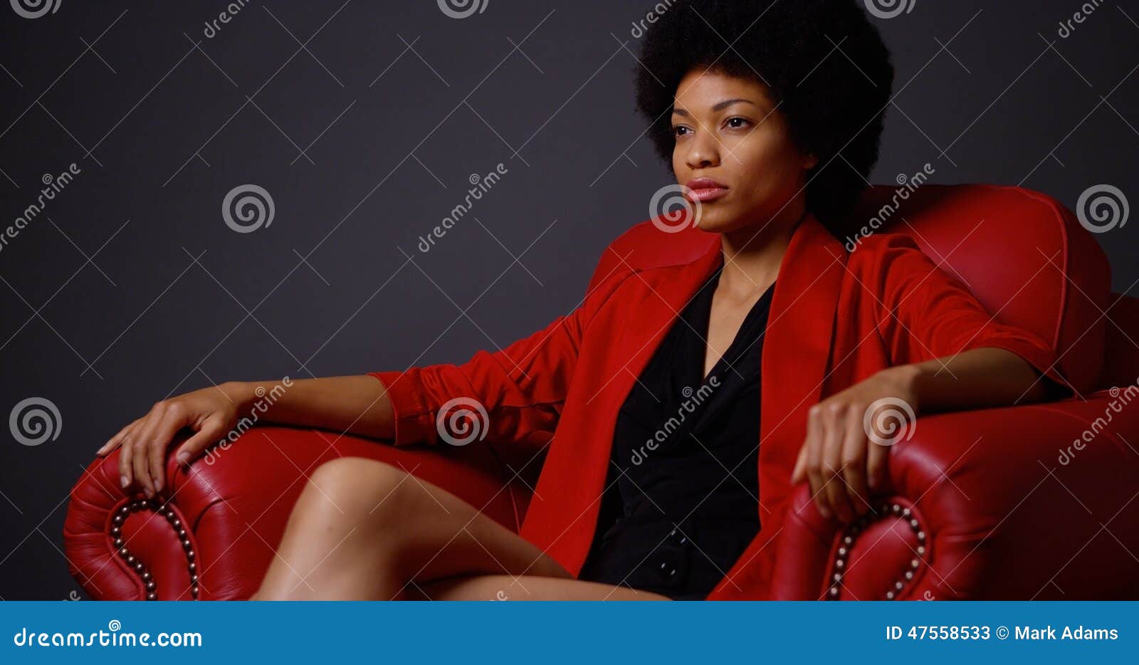 Femme De Couleur Attirante Forte S'asseyant Dans La Chaise Rouge Image