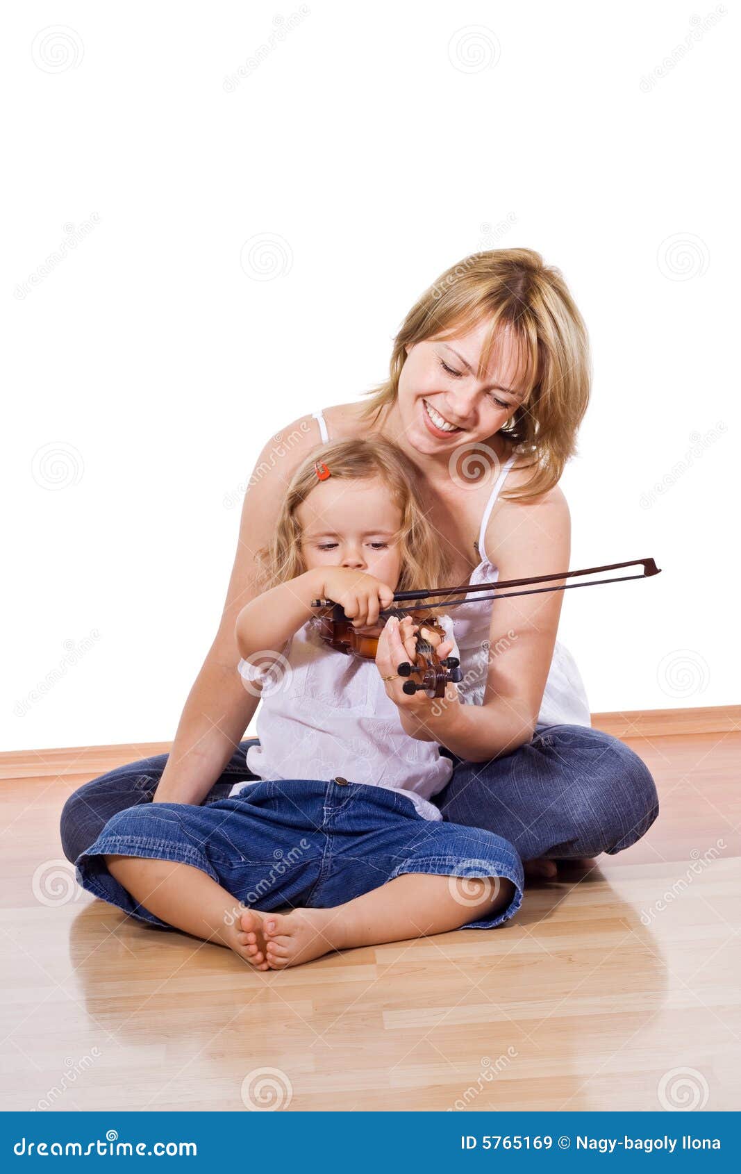 Femme enseignant la petite fille à jouer le violon. Femme s'asseyant sur l'étage avec une petite fille jouant et pratiquant le violon - d'isolement