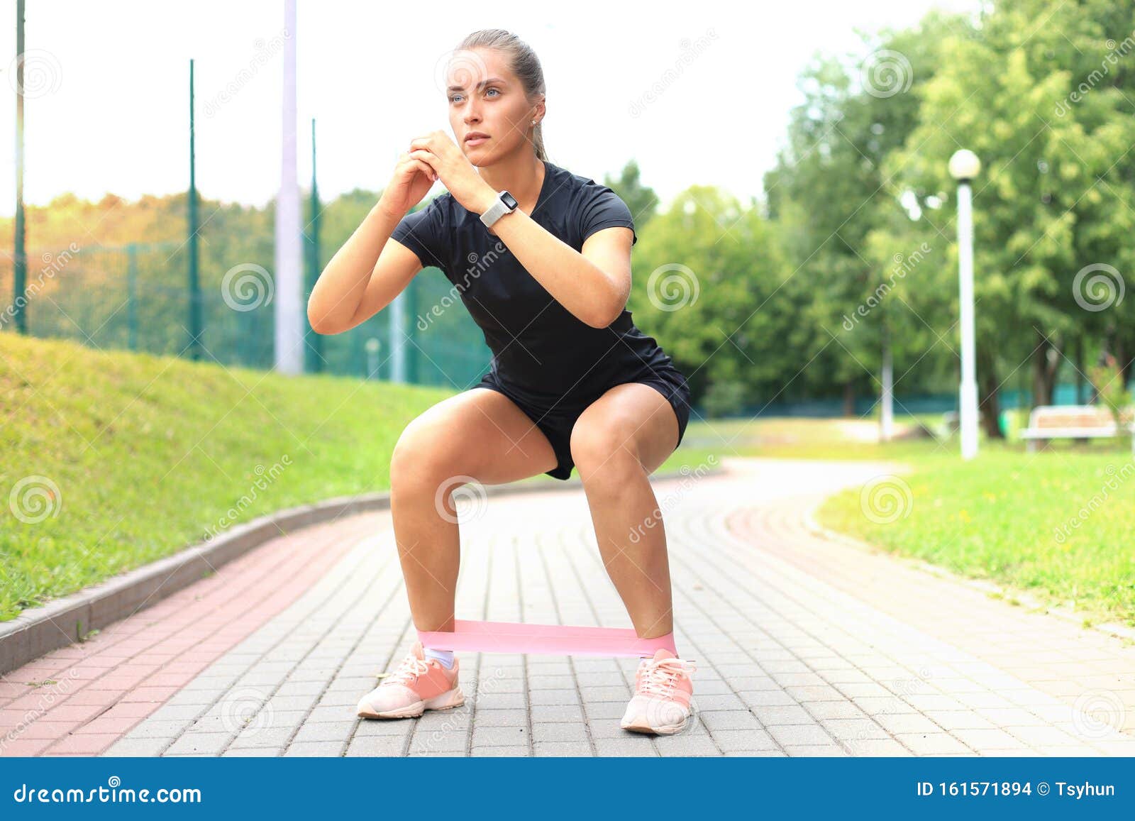 Femme Sportive Faisant Des Squats Avec Un Expanseur De Gomme Dans