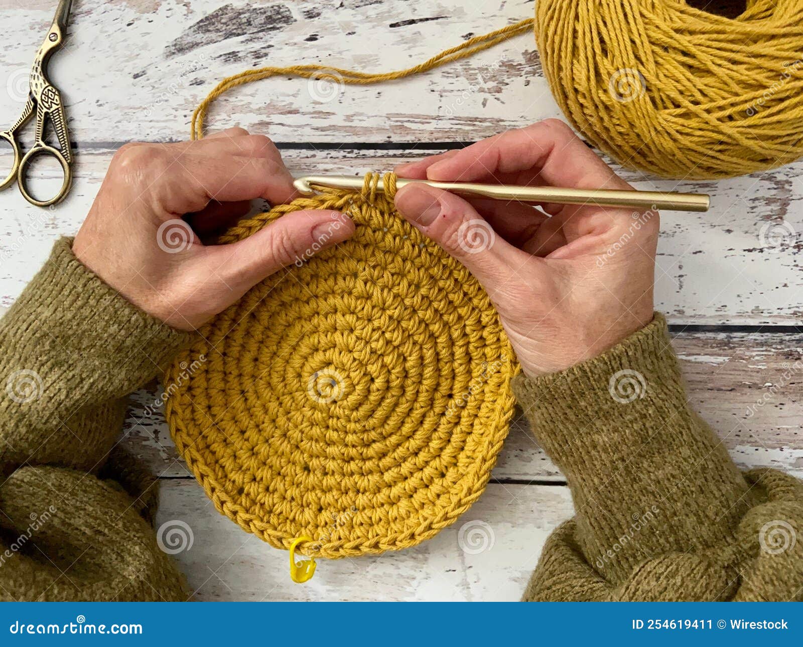 Femme Tricoter Un Crochet Placemat Rond Sur Une Surface En Bois Et Un  Ciseau Sur Son Côté Image stock - Image du coton, moutarde: 254619411
