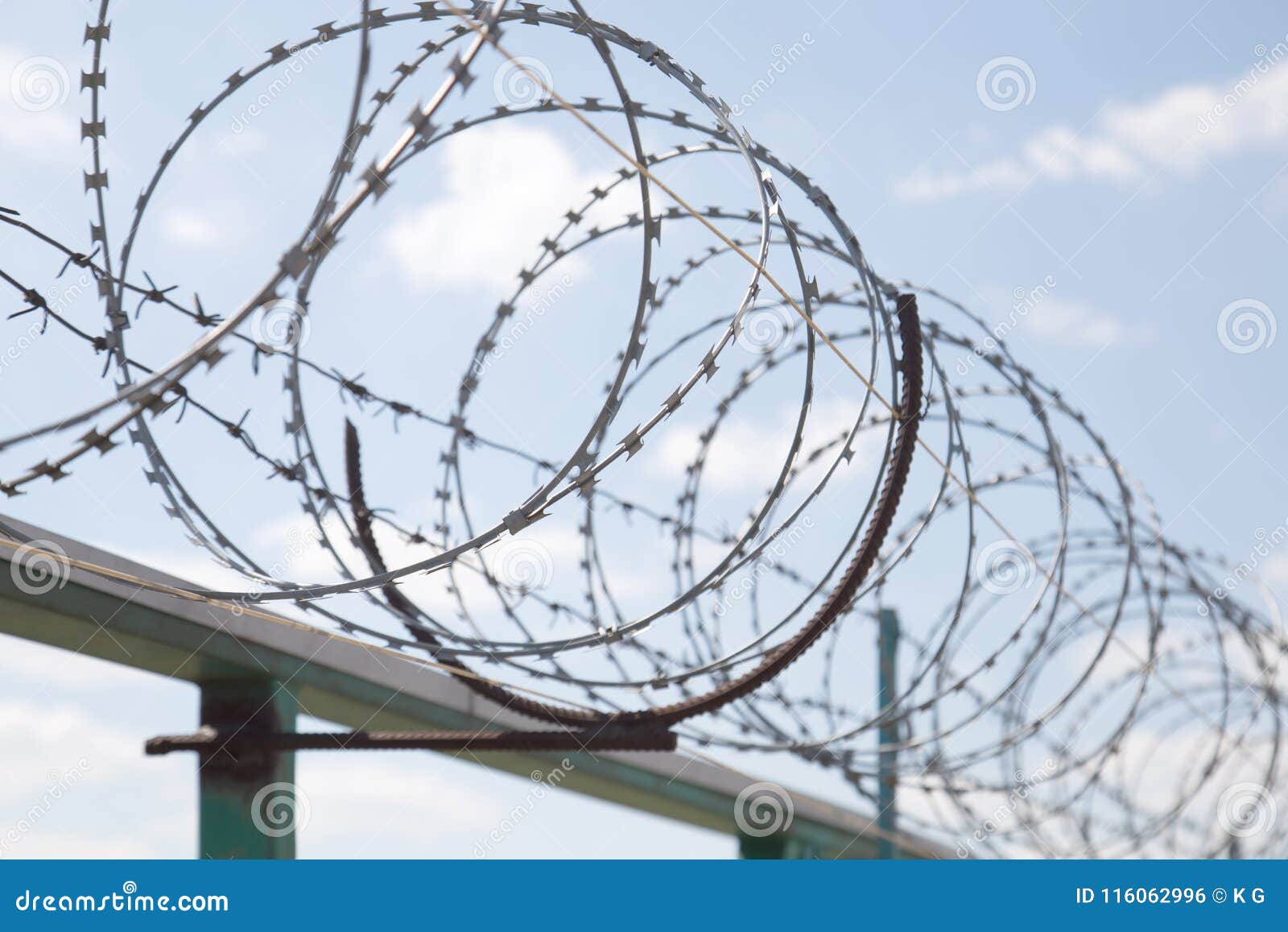 fence with razor barbed wire protection against blue sky background. dictatorship and tyranny concept