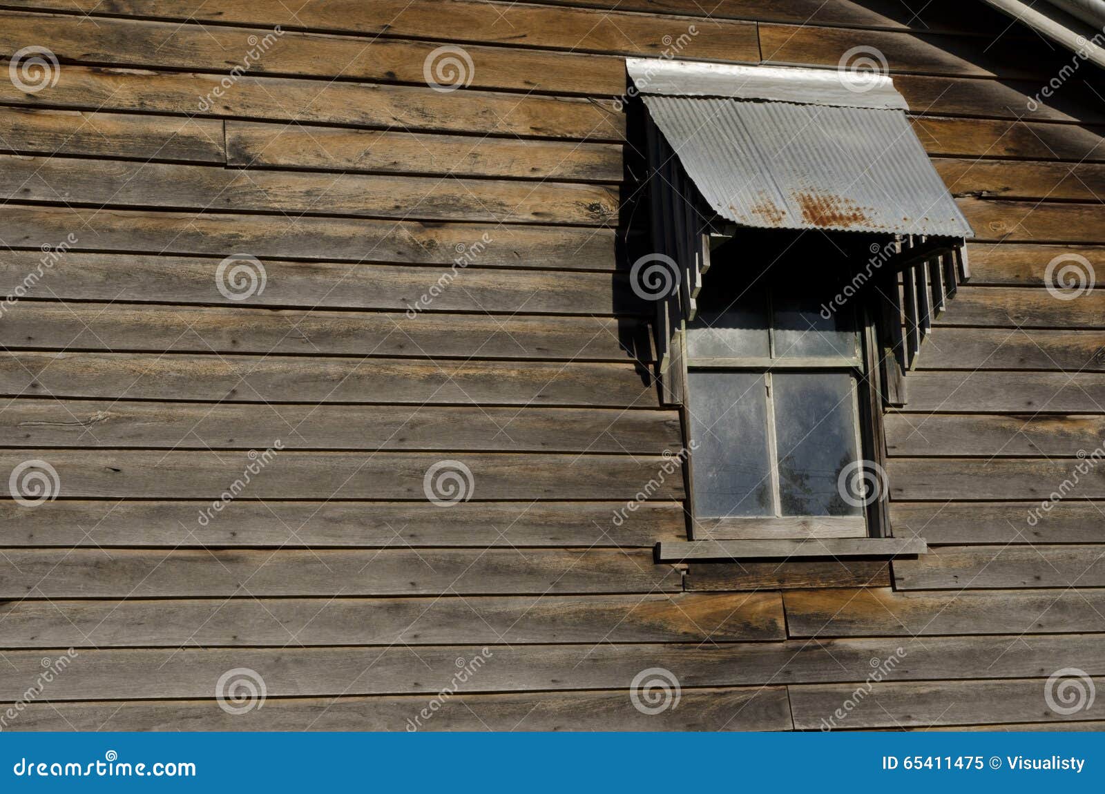 Fenêtre sur la vieille maison en bois. Détails d'une fenêtre et d'un mur d'une vieille maison ou grange en bois rustique Les plans en bois sur le mur sont temps déchiré et vieux La fenêtre a le verre sale et le toit rouillé en métal au-dessus de elle