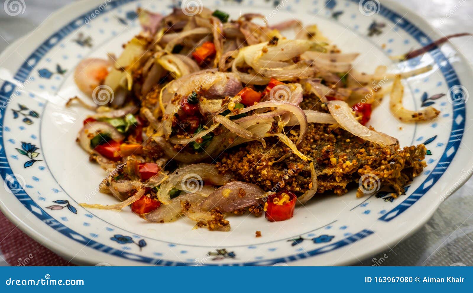 fermented fried freshwater bream fish with fried onion or ikan pekasam in a plate on table