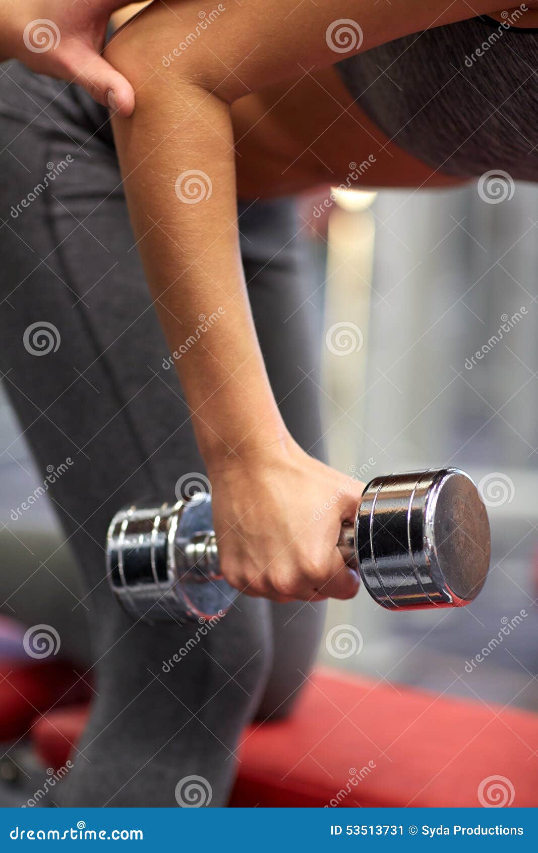 Fermez-vous des ajouter à l'haltère s'exerçant dans le gymnase. Concept de forme physique, de sport, d'exercice et d'haltérophilie - fermez-vous de la jeune femme et de l'entraîneur personnel avec des haltères fléchissant des muscles dans le gymnase