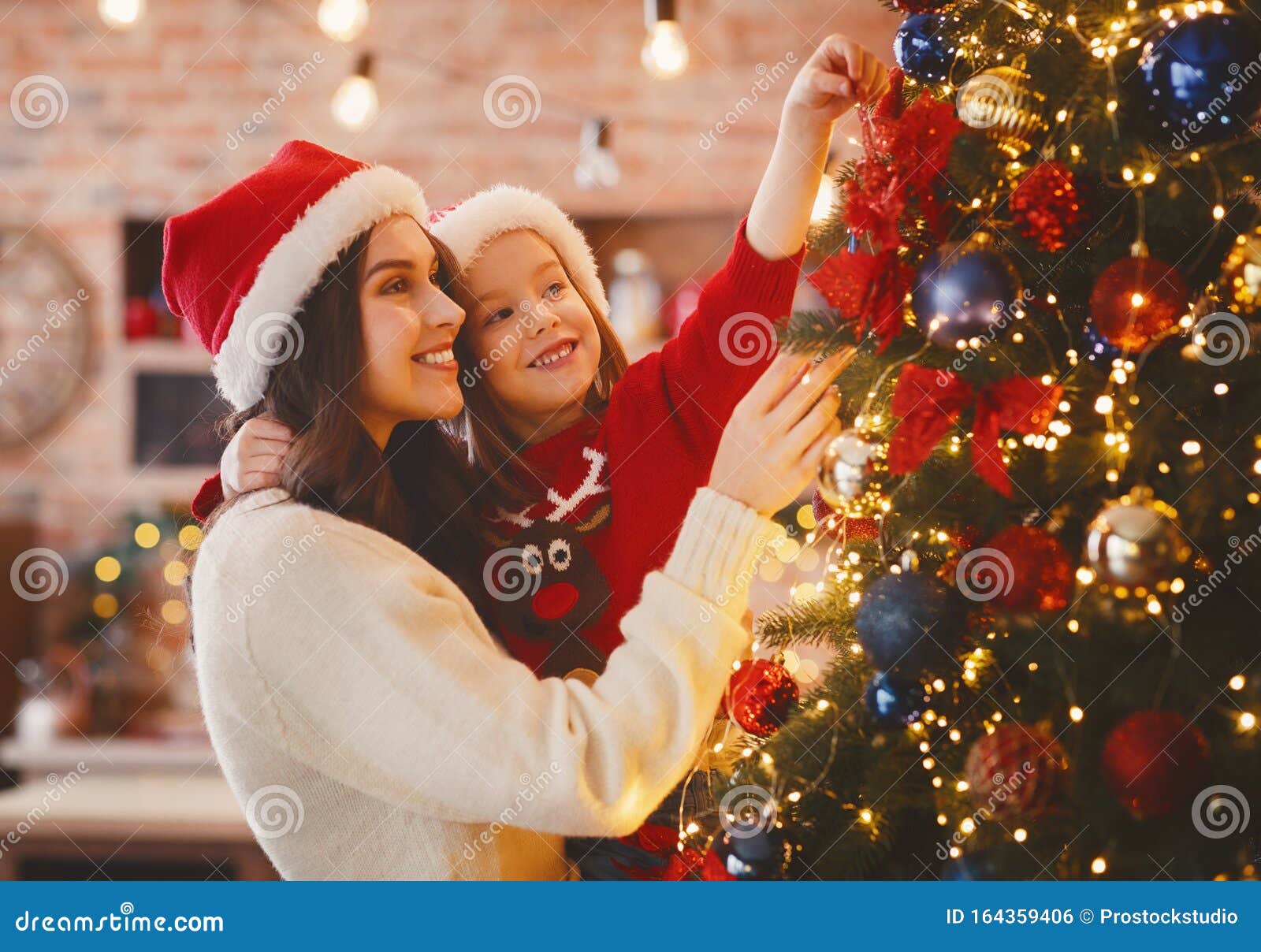 festive mother and daughter decorating christmas tree at home