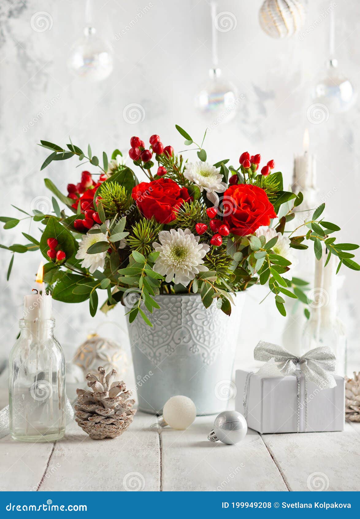 festive winter flower arrangement with red roses, white chrysanthemum and berries in vase on table decorated for holiday.