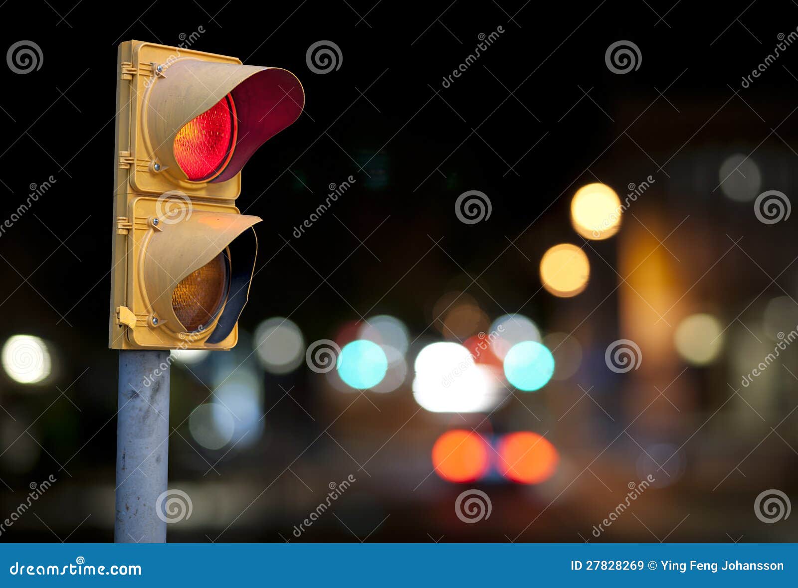 Le feu de signalisation rouge la nuit avec la ville s'allume à l'arrière-plan