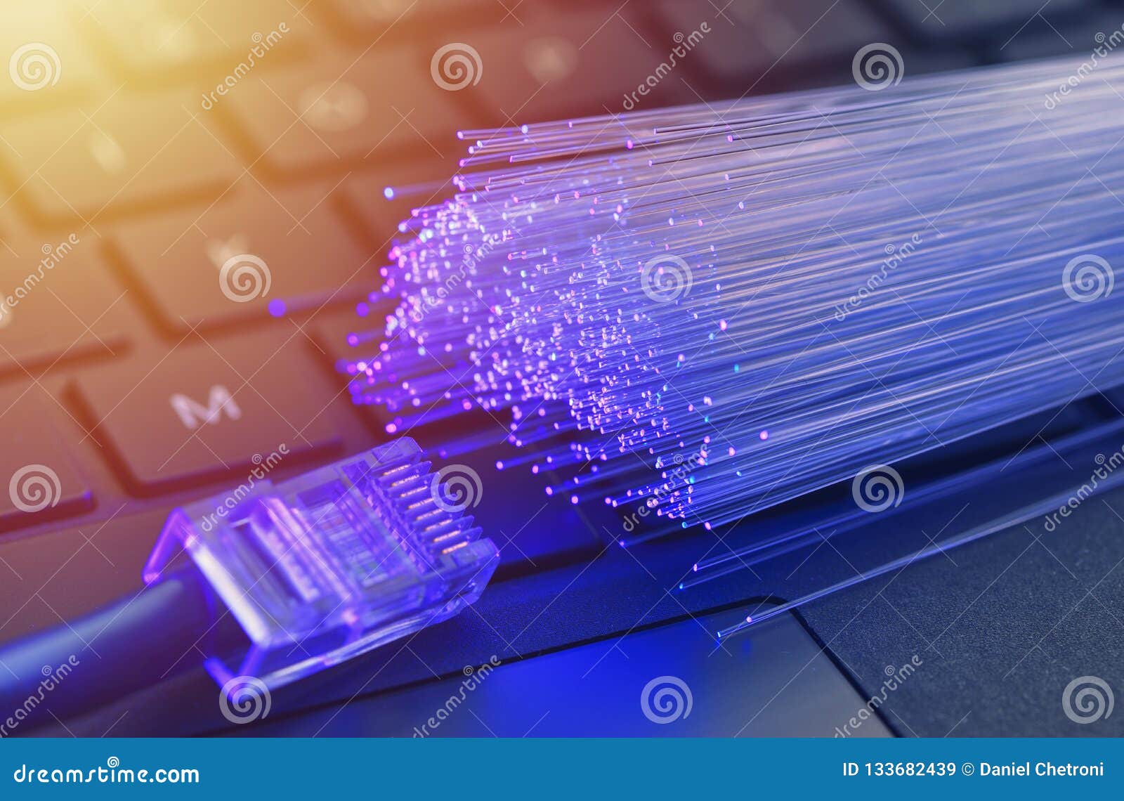 fiber optics in blue, close up with ethernet and keyboard background, warm lens flare