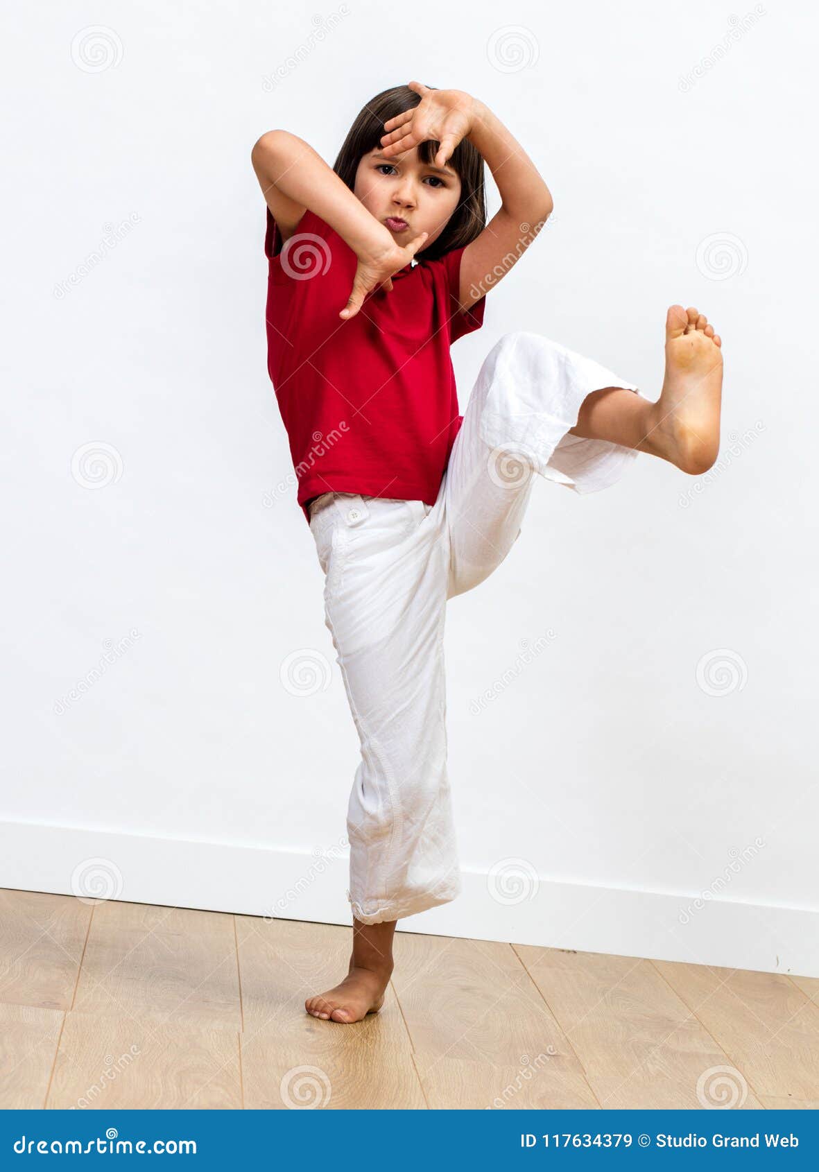 fighting child raising feet and playing hands to practise taekwondo