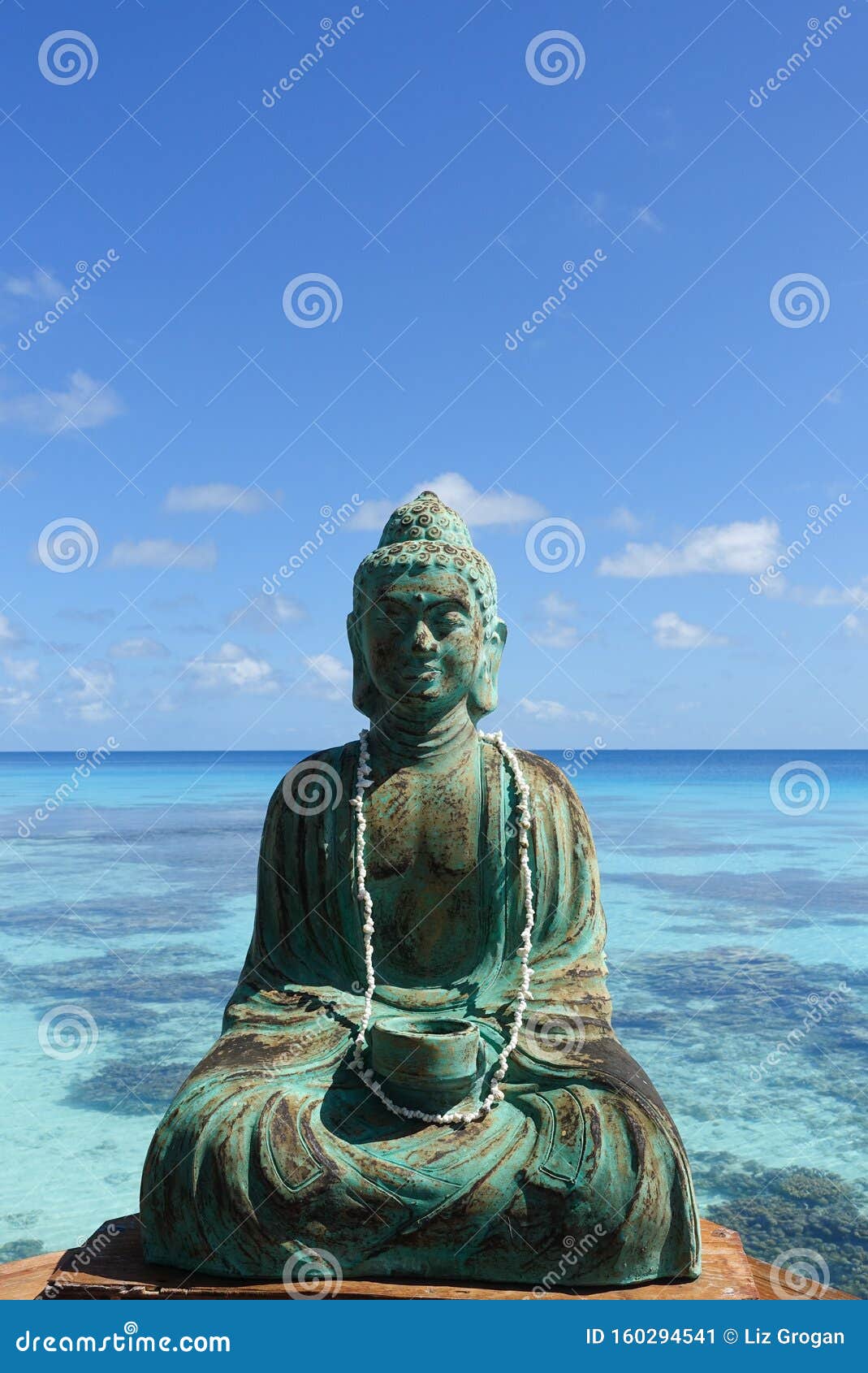 a figure of buddha in front of a turquoise lagoon on the island of fakarava in french polynesia in the south pacific; copy space