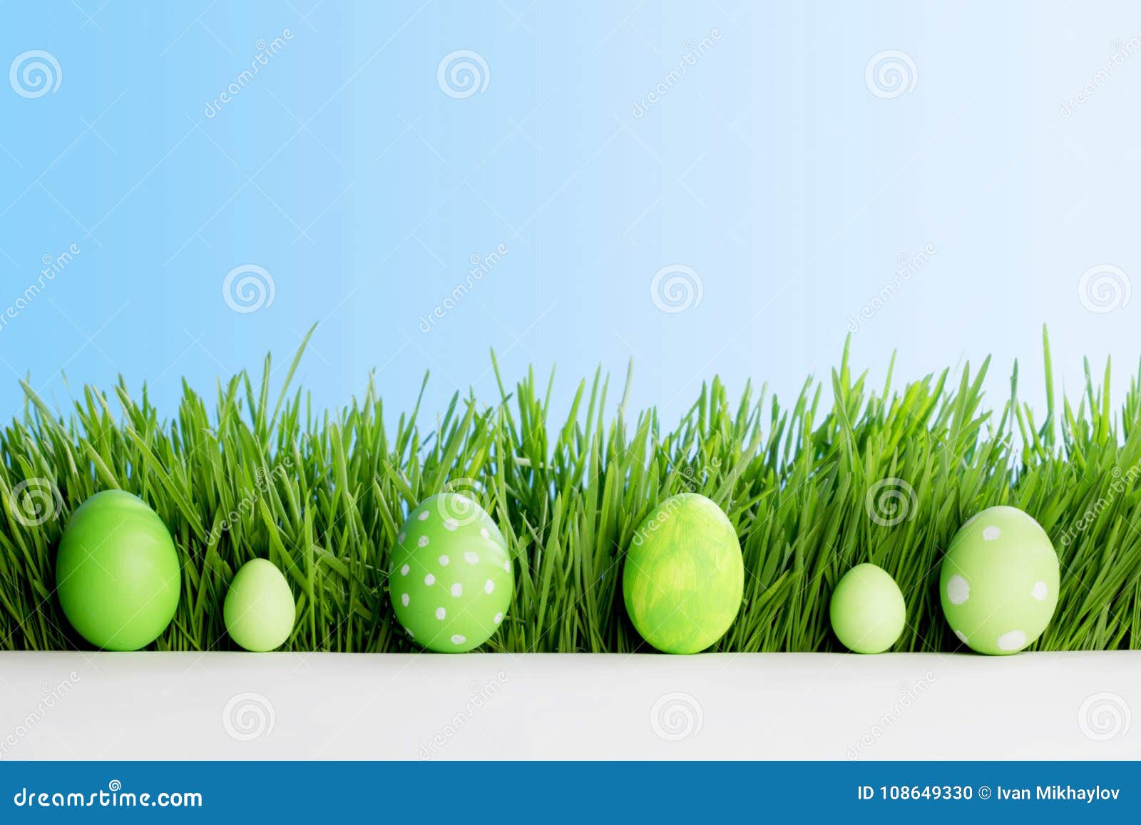 Fila de los huevos de Pascua en hierba verde fresca sobre fondo del cielo azul